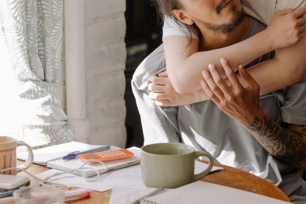 A wife with her arms around her husband, discussing their loan tenure for their home loan in Singapore