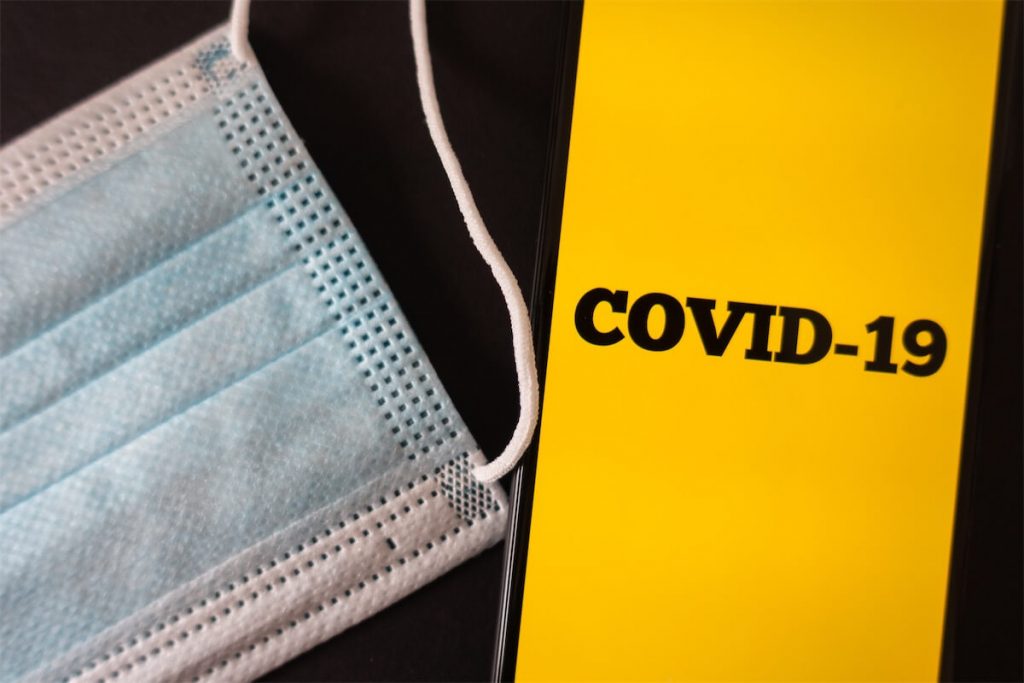  Image of a mask and a phone with the word ‘COVID-19’ 