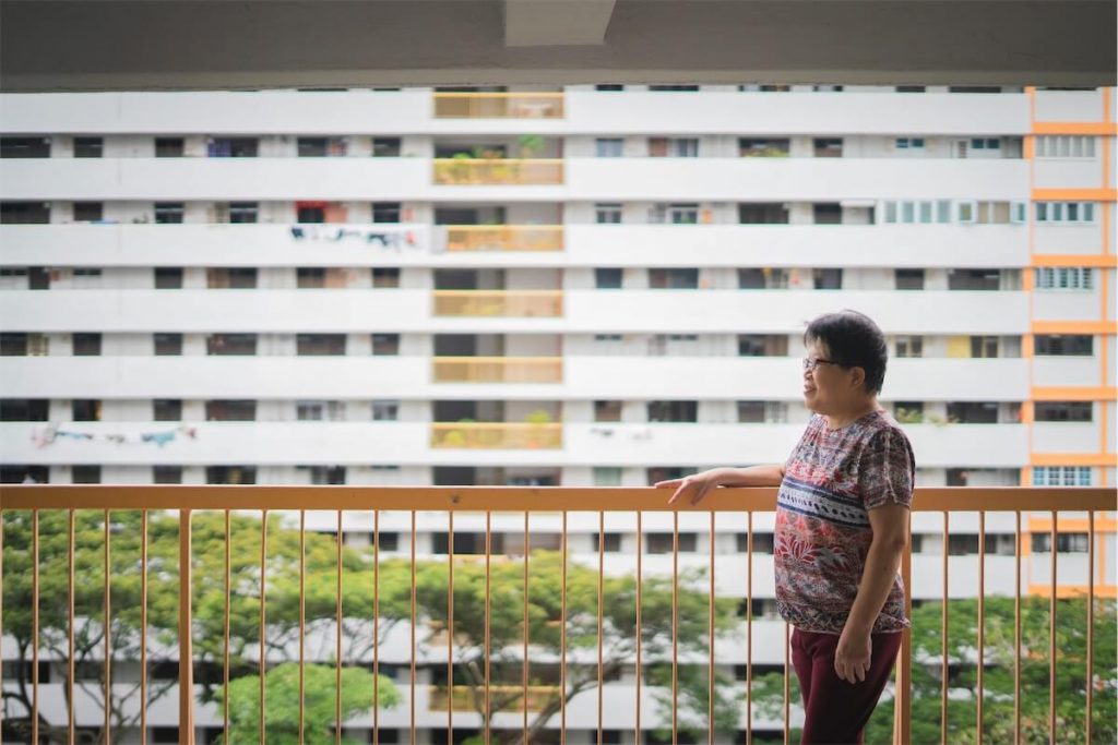 Woman posing in front of an HDB flat, thinking about her HDB loan in Singapore