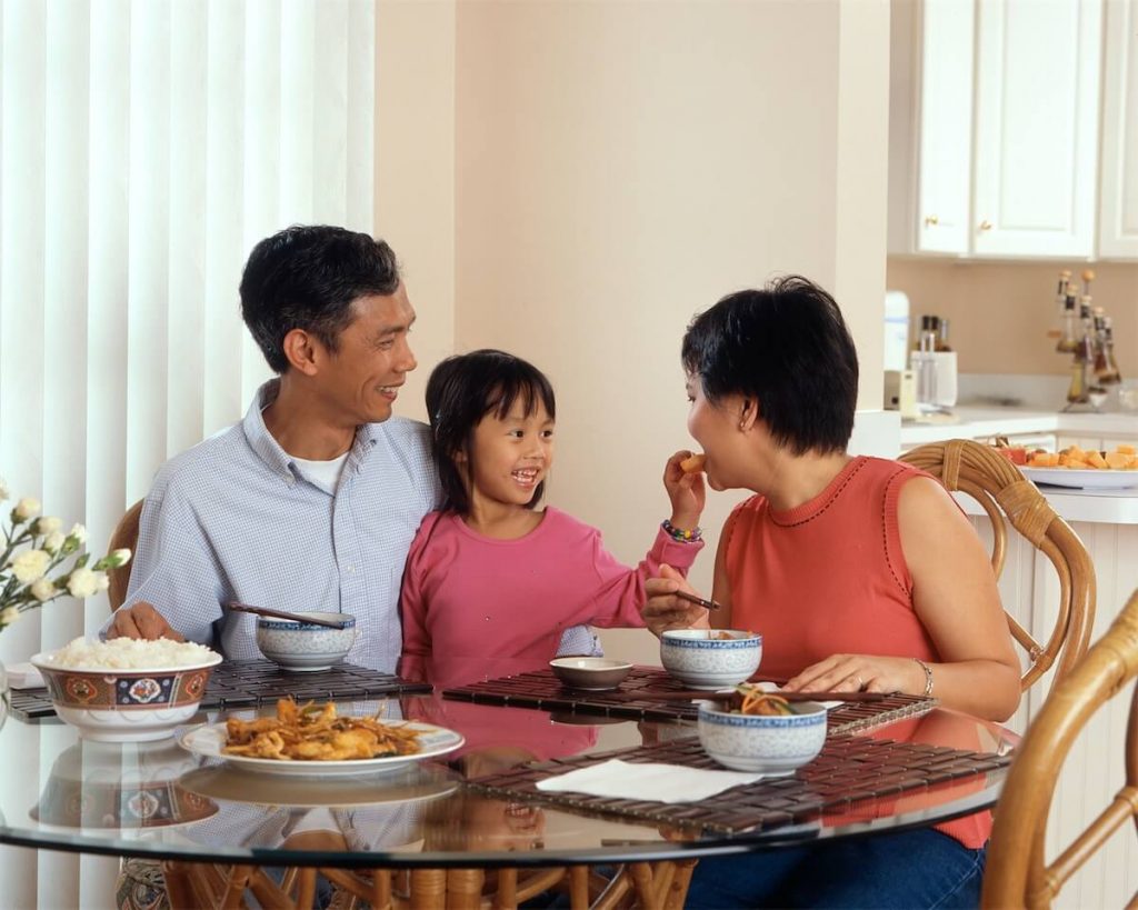 A family of three having dinner at the dining table. Another way of avoiding ABSD for your second property in Singapore is to buy a property under a trust for your children.