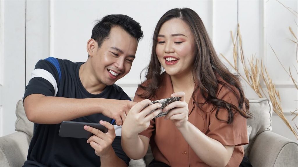  A young couple playing mobile games in their jointly bought HDB flat in Singapore