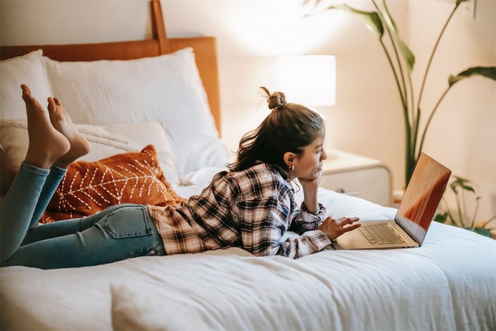 Woman researching on her eligibility for HDB Home Protection Scheme (HPS) in Singapore on her laptop in bed