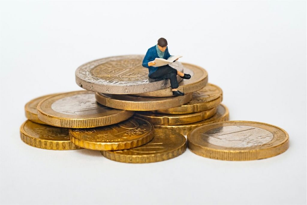 Miniature toy on top of a stack of coins depicting a person reviewing their home loan mortgage rate in Singapore.