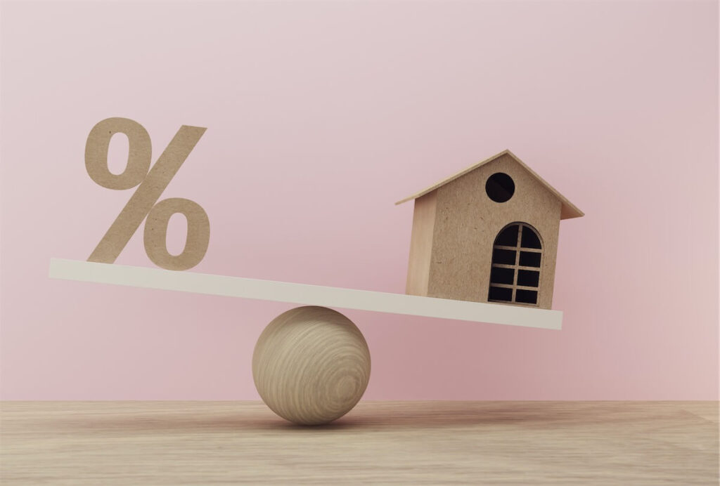Image of a percentage and home symbol on a see-saw, illustrating the concept of weight home loan interest rates during a home loan refinance