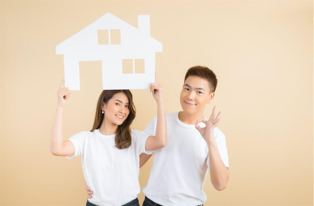 Young couple holding a cut-out paper house, showing that they are getting their first home and looking into Singapore's mortgage rates